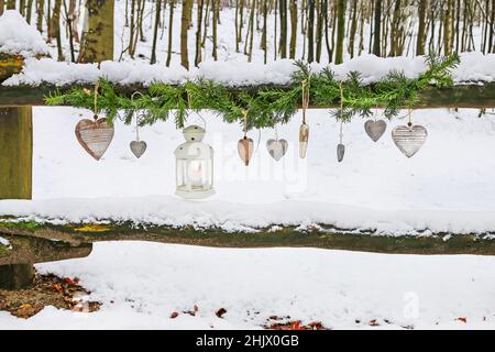 Guirlande de sapin, lanterne en fer et coeurs en bois suspendus dans le jardin d'hiver. Fête Banque D'Images