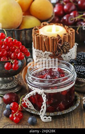 Pots de confiture de fraises de cerise parmi les fruits d'été et d'automne sur une table en bois. Banque D'Images