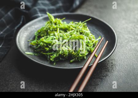 Wakame vert.Salade d'algues sur assiette noire. Banque D'Images
