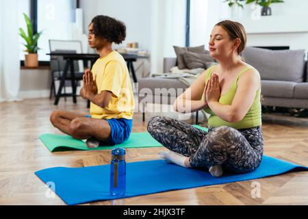 couple moderne multiethnique non stéréotypé faisant de la méditation le matin.Pas de stéréotypé petit ami et petite amie ensemble. Banque D'Images