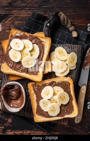 Toasts du pain avec des bananes et de la crème au chocolat sur une planche de bois.Arrière-plan en bois.Vue de dessus Banque D'Images