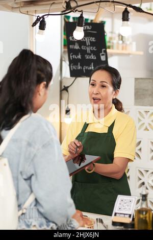 Fournisseur de chariots alimentaires donnant une tablette avec ordinateur au client Banque D'Images