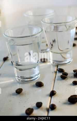 Sambuca en verres à liqueur et grains de café sur fond blanc Banque D'Images