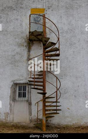 Vieux escalier en colimaçon rouillé menant à une porte fermée à l'extérieur d'un vieux bâtiment Banque D'Images