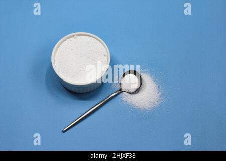 Poudre de collagène sur fond bleu. Supplément de santé naturel pour la peau Banque D'Images