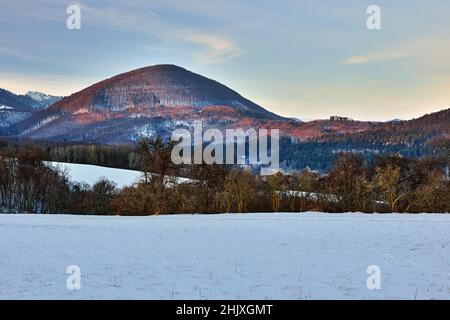 Paysage de montagne d'hiver illuminé par les derniers rayons du soleil couchant.Belles collines et forêt.Ciel bleu au coucher du soleil.Vrsatec, Slovaquie. Banque D'Images