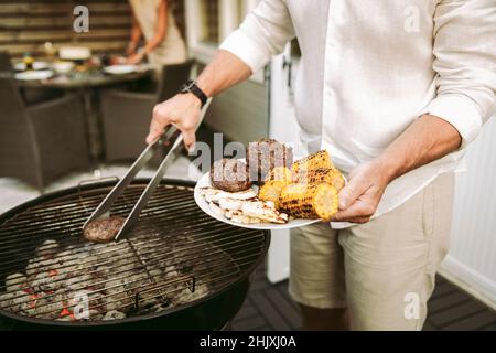 Section médiane de l'homme mûr préparant un repas barbecue dans la cour arrière Banque D'Images
