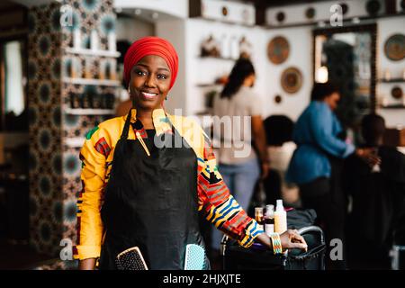 Portrait d'un coiffeur féminin confiant avec foulard dans un salon de coiffure Banque D'Images