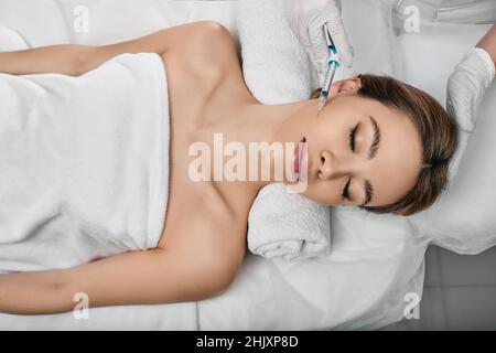 Esthéticienne faisant des injections de remplisseurs dermiques dans les joues féminines pour un visage plus jeune ou plus beau. injections de beauté Banque D'Images