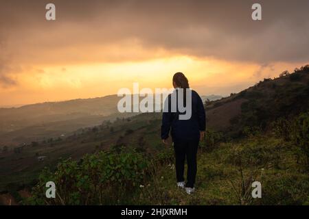 jeune fille debout sur le sommet de la montagne avec un arrière-plan de la chaîne de colline brumeux et le ciel dramatique au matin image est prise à badda pic shillong meghalaya inde Banque D'Images