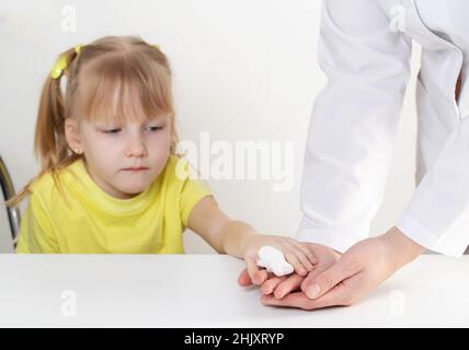Le médecin bandage la plaie avec un bandage, l'enfant est une fille de 5 ans Banque D'Images