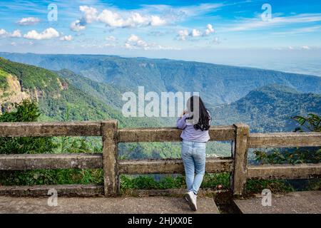 une jeune fille qui regarde la chaîne de montagnes avec un ciel bleu vif l'après-midi à partir d'une image d'angle plat est prise à la chute d'eau de sept sœurs cherrapunji meghalay Banque D'Images