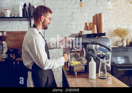 Un barista masculin utilise une machine à café professionnelle dans un café Banque D'Images