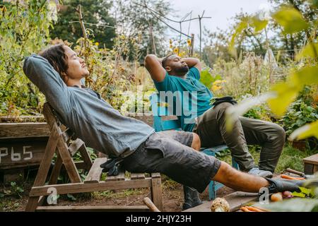 Les agriculteurs masculins reposent sur une chaise en bois dans le jardin urbain Banque D'Images