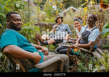 Joyeux volontaires hommes et femmes assis dans le jardin urbain Banque D'Images