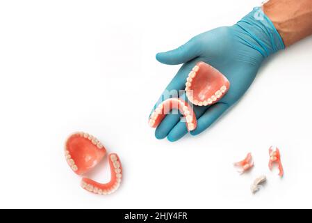 Dentiers sur fond blanc.Le dentiste tient des prothèses dentaires entre ses mains.Prothèse dentaire dans les mains du médecin en gros plan.Concept de dentisterie Banque D'Images