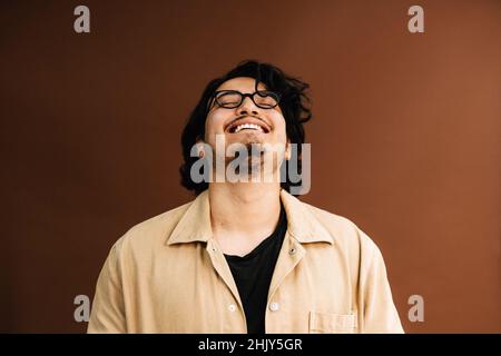 Homme joyeux avec les yeux fermés sur fond marron Banque D'Images