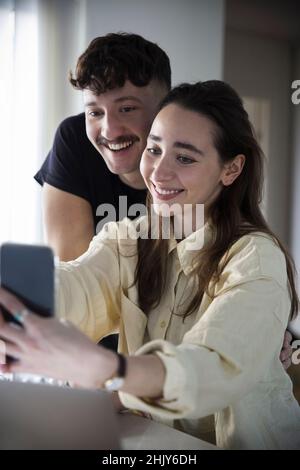 Couple heureux de prendre selfie sur smartphone à la maison Banque D'Images