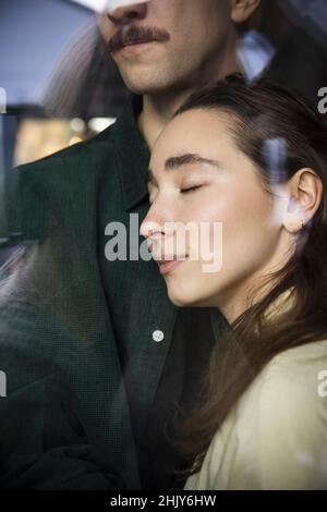 Femme avec les yeux fermés penchée sur le petit ami à la maison Banque D'Images