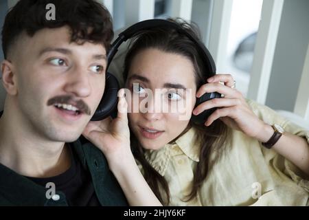 Couple hétérosexuel écoutant de la musique à travers des écouteurs à la maison Banque D'Images