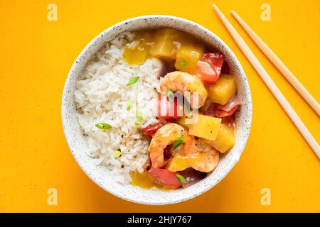 Curry d'ananas avec crevettes et riz blanc dans un bol sur fond jaune, vue du dessus Banque D'Images