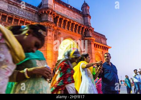 Mumbai, Maharashtra, Inde : les gens se rassemblent au crépuscule autour de la porte illuminée de l'Inde arche monumentale construite entre 1913 et 1924 dans l'Indo-Sara Banque D'Images