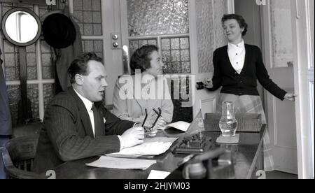 1950s, historique, un gentleman portant une épingle à rayures, qui convient à son bureau, un secrétaire à la porte et son assistante personnelle féminine, assis à ses côtés, Angleterre, Royaume-Uni. Banque D'Images