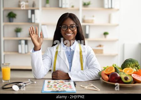 Portrait d'un nutritionniste afro-américain heureux donnant des consultations en ligne aux patients, ayant appel vidéo en clinique Banque D'Images