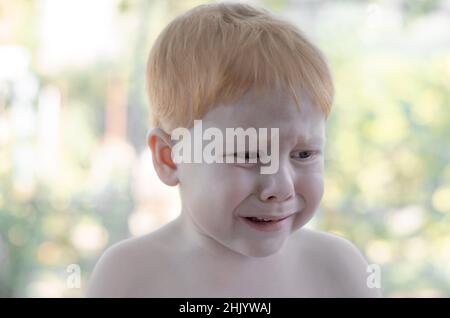 Le petit garçon aux cheveux rouges pleure.Un garçon de 4 ans est perdu dans le parc et pleure. Banque D'Images