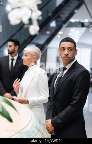 des gardes du corps multiethniques protègent les femmes d'affaires matures qui se sont arrivées à la réception de l'hôtel Banque D'Images