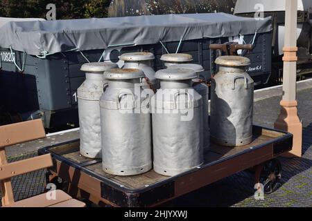 Des churns de lait d'époque sur le chariot à plate-forme à la gare de Totnes Riverside sur le South Devon Railway. Banque D'Images