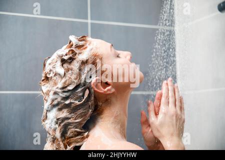 Vue arrière d'une femme prenant une douche dans la salle de bains. Banque D'Images