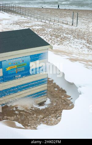 Une hutte de plage dans la neige sur Margate main Sands avec un chien marcheur au loin, Margate, Kent Banque D'Images