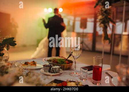 Accent sélectif sur la table de mariage avec des boissons et de la nourriture en arrière-plan newlyweds dansant la première danse Banque D'Images