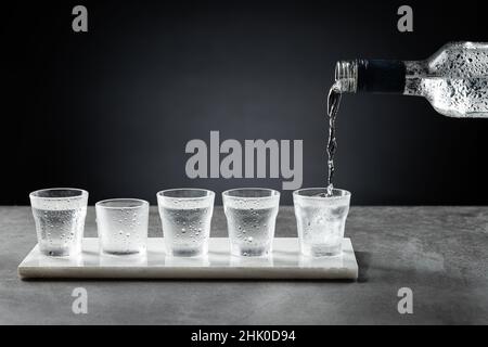 Verser de la vodka froide dans un verre à plomb isolé sur fond sombre.Mise au point sélective. Banque D'Images