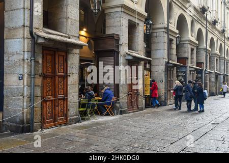 Les gens font la queue pendant la pause déjeuner pour accéder à un restaurant sous les arcades de la via Palazzo di Città dans le centre historique de Turin, Piémont Banque D'Images