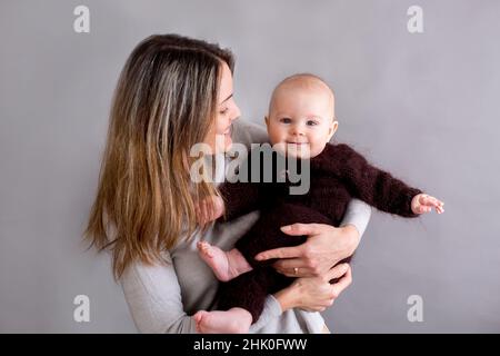 Jeune mère, caressant son nouveau-né garçon, le tenant dans ses bras, différentes positions de tenir bébé, souriant du bonheur Banque D'Images