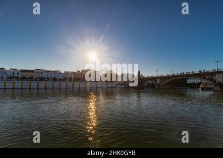 Coucher de soleil sur le fleuve Guadalquivir dans le centre de Séville avec des couleurs étonnantes dans le ciel et une vue sur le bord de la rivière du quartier Triana. Banque D'Images