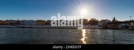 Coucher de soleil sur le fleuve Guadalquivir dans le centre de Séville avec des couleurs étonnantes dans le ciel et une vue sur le bord de la rivière du quartier Triana. Banque D'Images