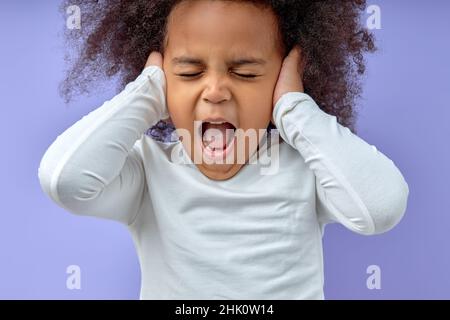 Photo de jeune fille malheureuse proche oreilles irrité problème stressé ignorer, fou en colère peur enfant couvrant les oreilles hurlant se sentant agacé, outrage Banque D'Images