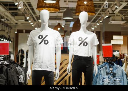 Deux mannequins mannequins portant des chemises blanches avec affiche pour cent dans le magasin de vêtements.Concept de remises sur les ventes.Vendredi noir. Banque D'Images