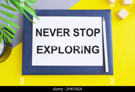 Composition Flat lay avec texte ne cessez jamais d'explorer sur le livre blanc au-dessus de Notebook , vue du dessus. Banque D'Images