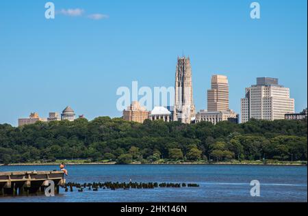 Vue sur New York sur le sentier de randonnée de l'Hudson River.Avec un homme assis sur un quai et une vue sur la tombe de Grant et l'église Riverside. Banque D'Images