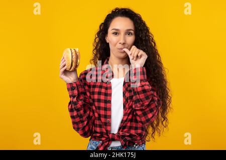 Happy Raughing Lady Eating Burger au Studio Banque D'Images