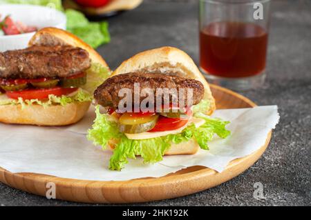 Hamburgers faits maison sur une assiette en bois.Gros plan. Banque D'Images