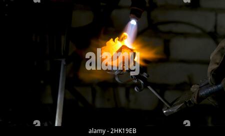 Le forgeron aligne les feuilles de rose de fer et fait la forme finale de la fleur.Forgeron fait une rose de fer. Banque D'Images