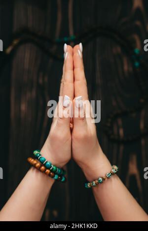 Femme lisant des mantras ou des prières, mains pliées en namaste devant le rosaire ou perles de mala sur fond en bois.Spiritualité, religion, Dieu Banque D'Images