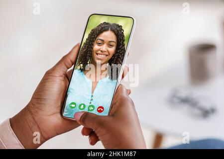 Femme noire tenant un téléphone portable dans la main appel vidéo à distance ami Banque D'Images