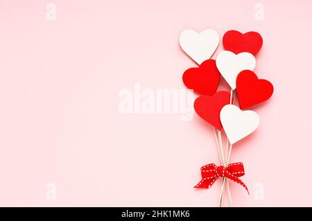 Contexte de la Saint-Valentin.Coeurs en bois rouge et blanc sur fond rose clair.Carte de vœux de fête.Plan à plat, espace de copie pour le texte Banque D'Images