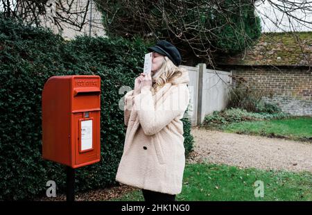 une femme a joint une lettre avec un baiser l'affichant dans une boîte postale anglaise Banque D'Images